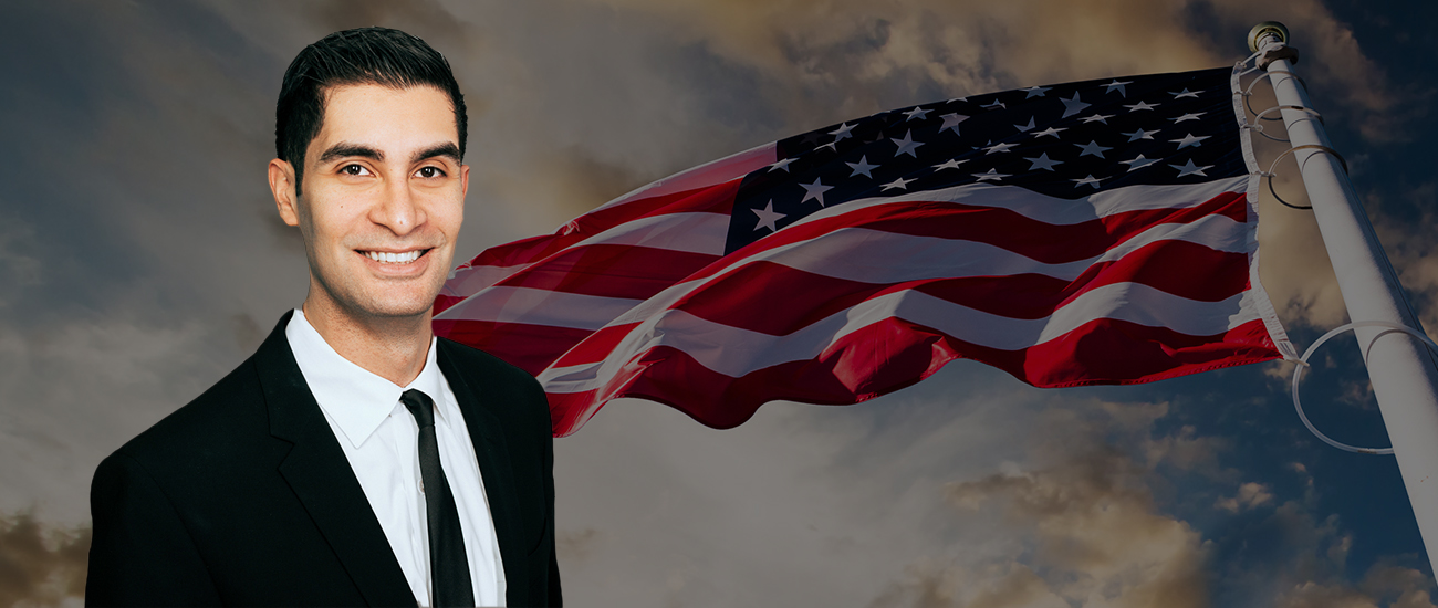 Armand Jawanmardi with a photograph of a raised USA flag with a dark filter, fluttering in the wind.